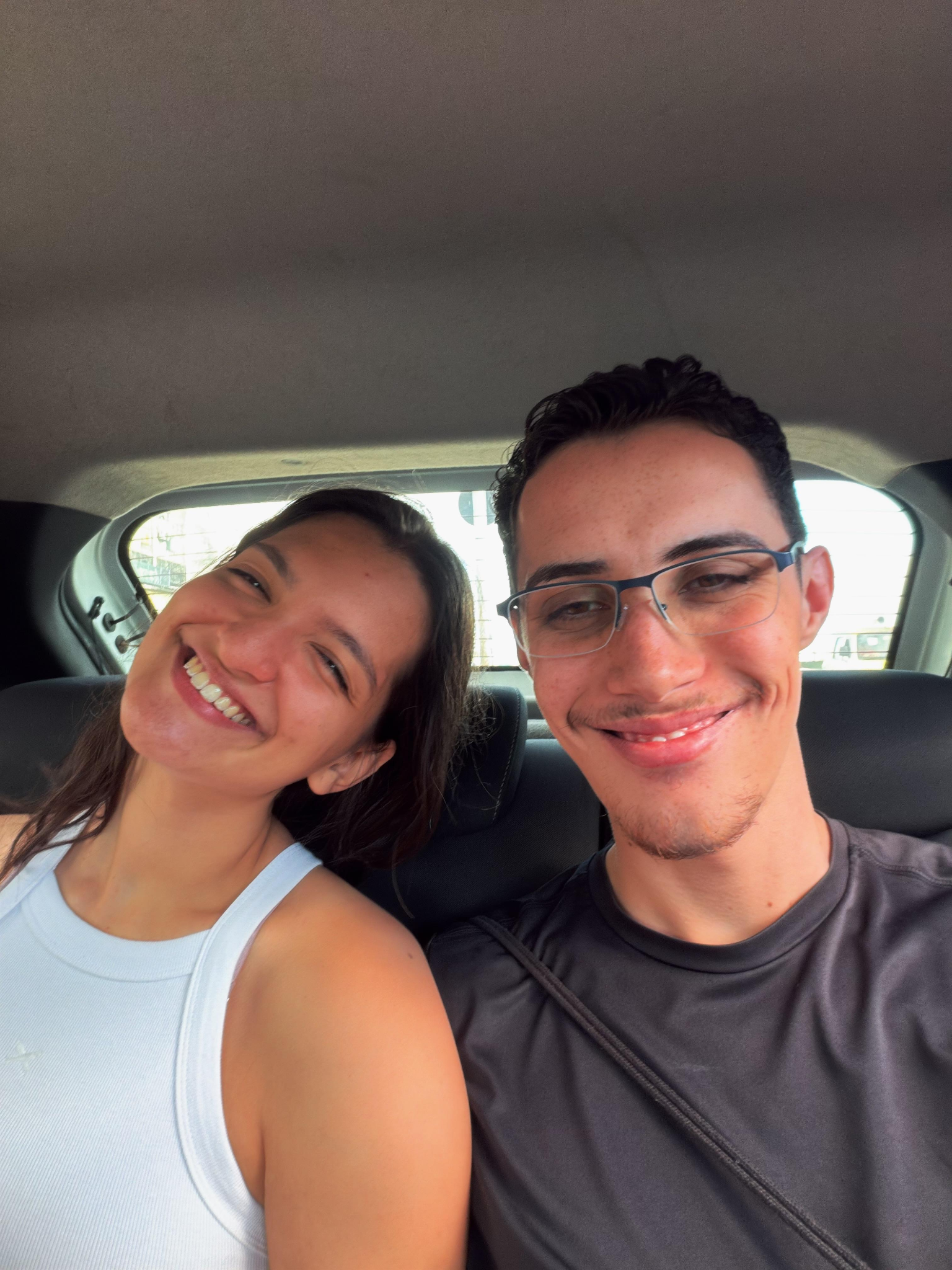 Sophia e Kauê sorrindo juntos no carro